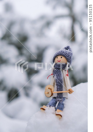 Angel gnome in scarf and knitted hat skiing on snowy fir branch Elf toy on skis in snowy landscape Copy space for text. New year and Merry christmas greeting card background. Ski winter resort Angel gnome in scarf and knitted hat skiing on snowy fir branch Elf toy on skis in snowy landscape Copy space for text. New year and Merry christmas greeting card background. Ski winter resort 95150135