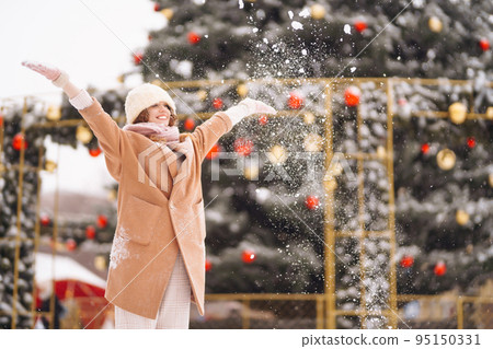 Young woman in winter style clothes posing at festive street market. Cold weather. Winter fashion, holidays. Young woman in winter style clothes posing at festive street market. Cold weather. Winter fashion, holidays. 95150331