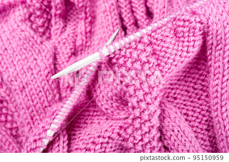 Knitting project of pink wool sweater in progress. 95150959