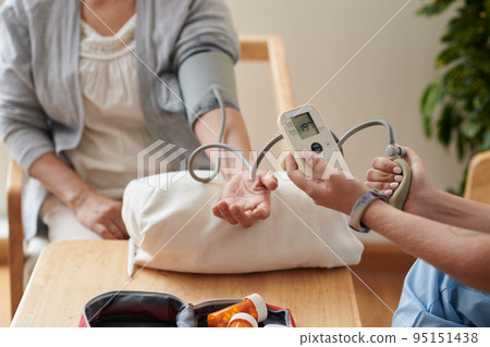 Close-up of nurse checking blood pressure of patient with special medical equipment at table 95151438