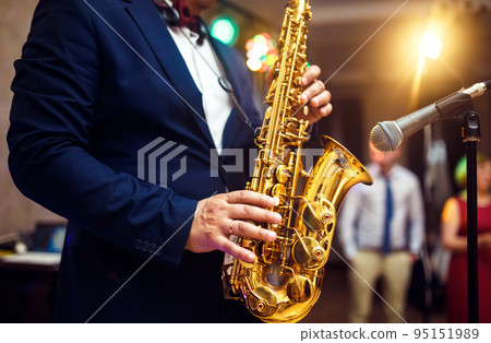 young musician man plays tenor saxophone on stage with light bokeh effected over blurred music. young musician man plays tenor saxophone on stage with light bokeh effected over blurred music. 95151989