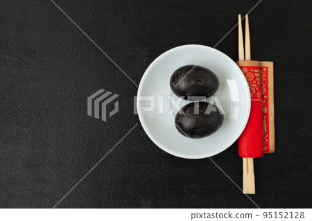 Black eggs hard-boiled in sulfuric hot springs and chopsticks on a black background 95152128