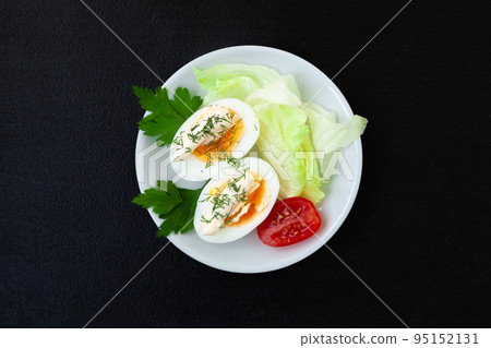 Hard boiled eggs with mayonnaise, lettuce and tomatoes on a plate  on a dark background 95152131