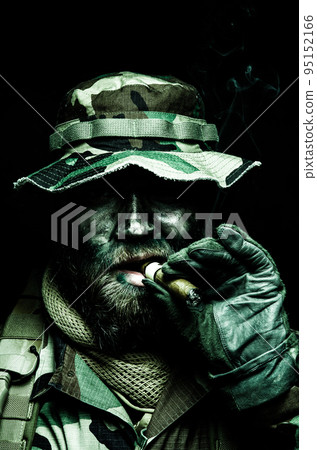 Brutal and serious commando soldier, army special forces veteran, in camouflage battle uniform, boonie hat, black paint on bearded face, combat knife in shoulder holder, smoking cigar, studio portrait Brutal and serious commando soldier, army special forces veteran, in camouflage battle uniform, boonie hat, black paint on bearded face, combat knife in shoulder holder, smoking cigar, studio portrait 95152166