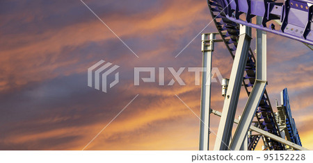 Attraction roller-coaster (switchback) against the background of a romantic evening sky Attraction roller-coaster (switchback) against the background of a romantic evening sky 95152228