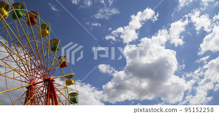 Attraction (carousel) ferris wheel on the background of the cloudy sky Attraction (carousel) ferris wheel on the background of the cloudy sky 95152258