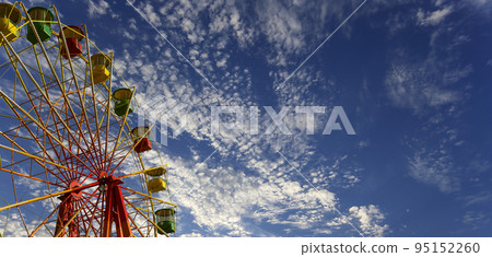 Attraction (carousel) ferris wheel on the background of the cloudy sky Attraction (carousel) ferris wheel on the background of the cloudy sky 95152260