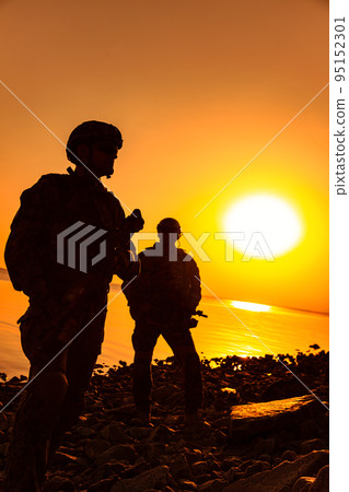 Army soldiers with rifles orange sunset silhouette in action during raid on the river coast Army soldiers with rifles orange sunset silhouette in action during raid on the river coast 95152301