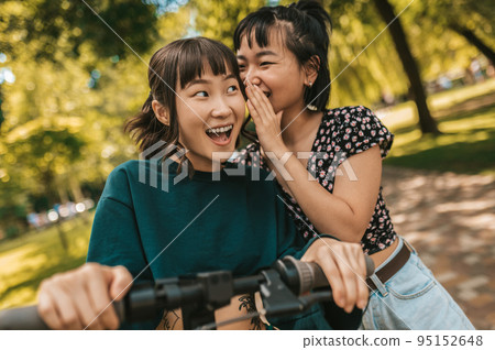 Girls in the park sharing secrets and looking interested 95152648