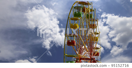 Attraction (carousel) ferris wheel on the background of the cloudy sky Attraction (carousel) ferris wheel on the background of the cloudy sky 95152716