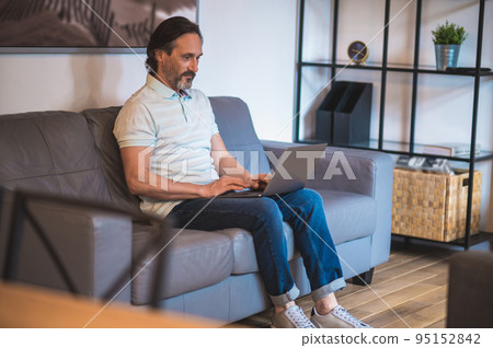 Mature dark-haired man working remotely from home Mature dark-haired man working remotely from home 95152842
