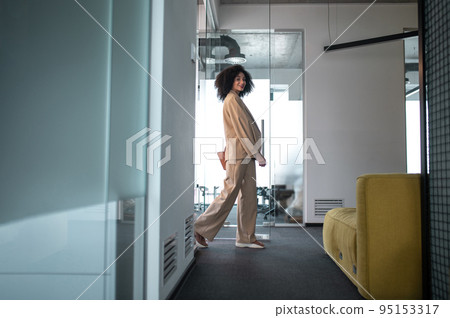 Young woman in beige suit walking in the office corridor Young woman in beige suit walking in the office corridor 95153317