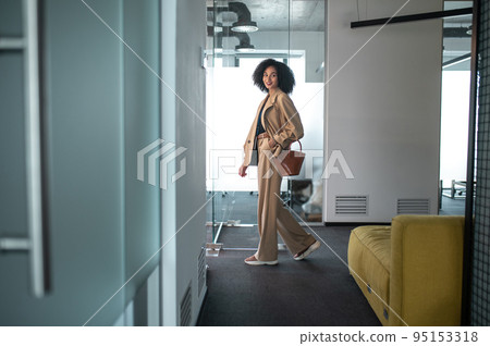 Confident and determined businesswoman entering a modern office with glass doors Confident and determined businesswoman entering a modern office with glass doors 95153318