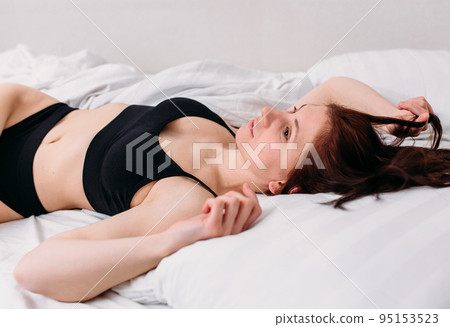 Portrait of a young beautiful brunette lying in bed wearing underwear Portrait of a young beautiful brunette lying in bed wearing underwear 95153523