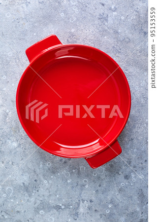 Empty red round ceramic baking dish on gray background 95153559