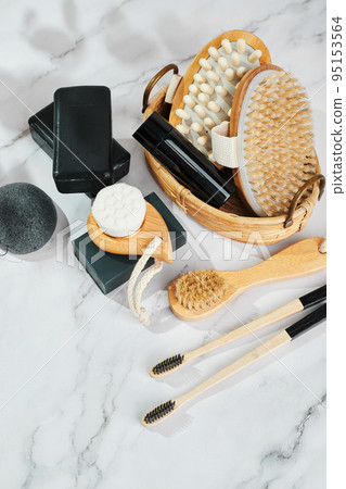 Three pieces of black charcoal soap, Konjac sponge, beauty care products, candles, black charcoal toothbrushes and brushes for washing and massage on marble background 95153564