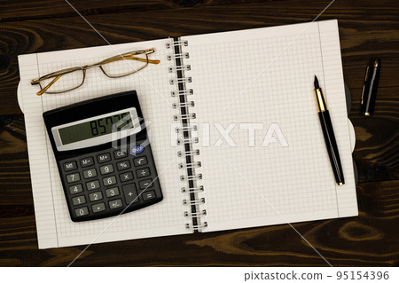 Top view office table desk. Financial report. Flat lay. Workspace with Business office supplies, empty sheet of paper, pen, glasses, calculator on the table. Copy space for text. Top view. Close-up Top view office table desk. Financial report. Flat lay. Workspace with Business office supplies, empty sheet of paper, pen, glasses, calculator on the table. Copy space for text. Top view. Close-up 95154396