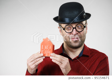 Man wearing funny eyeglasses holding house 95154671