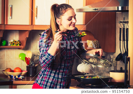 Woman frying frozen vegetables. Stir fry. 95154750