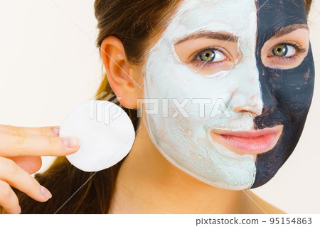 Girl remove black white mud mask from face 95154863