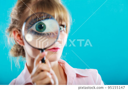 Woman hand holding magnifying glass on eye 95155147