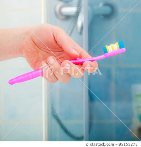 Woman hand holding toothbrush in bathroom Woman hand holding toothbrush in bathroom 95155275