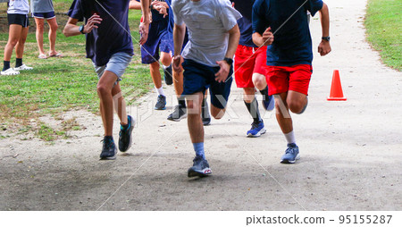 Group of runners running together on a dirt path in a park Group of runners running together on a dirt path in a park 95155287