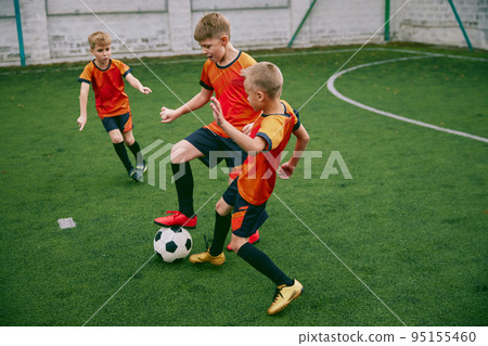 Workout. Junior soccer team playing football at sports stadium, outdoors. Concept of sport, competition, studying and achievements 95155460