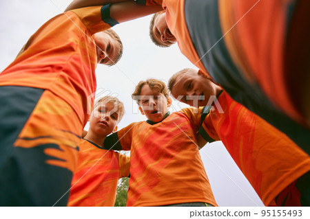 Support, motivation. Children, junior soccer team standing together in circle. Concept of sport, competition, studying and achievements. Bottom view Support, motivation. Children, junior soccer team standing together in circle. Concept of sport, competition, studying and achievements. Bottom view 95155493