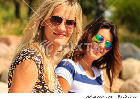 Happy women sun tanning and relaxing on beach. 95156516