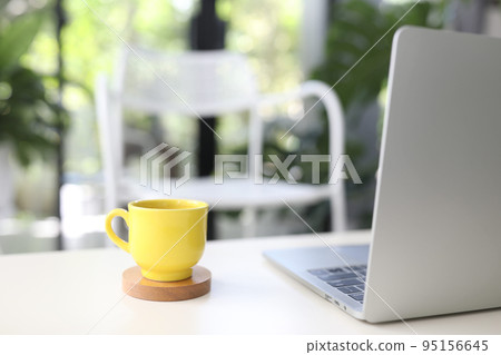 Laptop and yellow coffee cup on white table indoor work from home Laptop and yellow coffee cup on white table indoor work from home 95156645