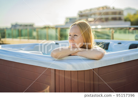 Portrait of young carefree happy smiling woman relaxing at hot tub during enjoying happy traveling moment vacation life against the background of green big mountains Portrait of young carefree happy smiling woman relaxing at hot tub during enjoying happy traveling moment vacation life against the background of green big mountains 95157396