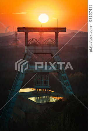 Vertical shot of a headframe tower with a golden sun setting in the background in Herten, Germany 95157453