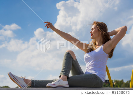 Girl wearing trousers and sneakers pointing outdoor 95158075