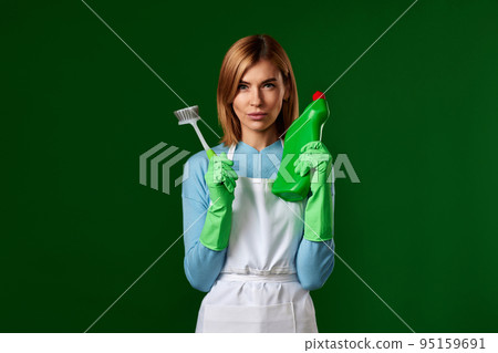 woman in gloves holding brush and bottle of detergent woman in gloves holding brush and bottle of detergent 95159691