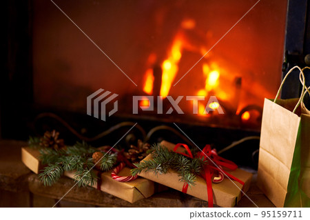 New Year or Christmas Gift Box with Red Ribbon. Fireplace background New Year or Christmas Gift Box with Red Ribbon. Fireplace background 95159711