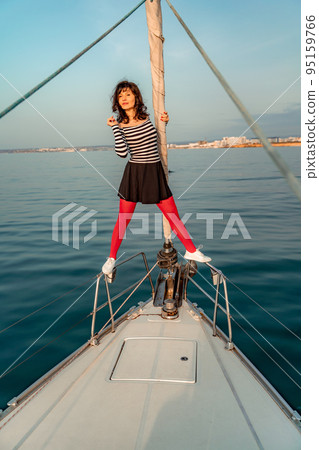 Woman standing on the nose of the yacht at a sunny summer day, breeze developing hair, beautiful sea on background Woman standing on the nose of the yacht at a sunny summer day, breeze developing hair, beautiful sea on background 95159766