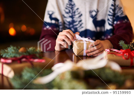 Men's hands hold Christmas present. Man using ribbon, green fir tree twig to create Christmas gift. Men's hands hold Christmas present. Man using ribbon, green fir tree twig to create Christmas gift. 95159993