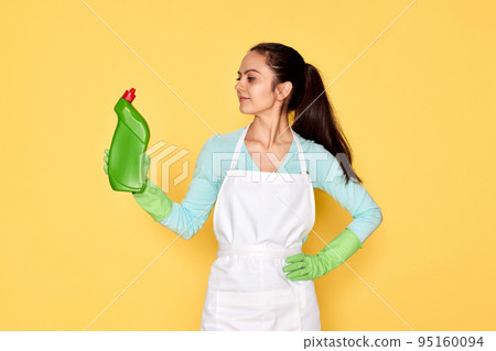 woman in gloves and cleaner apron holding bottle of detergent woman in gloves and cleaner apron holding bottle of detergent 95160094