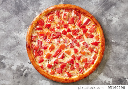 Browned pizza with juicy tomatoes, melted mozzarella and italian herbs on gray stone surface Browned pizza with juicy tomatoes, melted mozzarella and italian herbs on gray stone surface 95160296