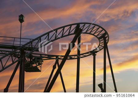 Attraction roller-coaster (switchback) against the background of a romantic evening sky 95161064