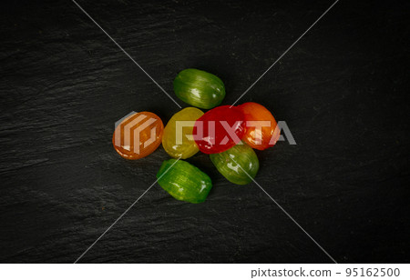 Colorful Hard Candies Pile on Black Texture Background 95162500