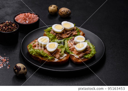 Delicious fresh sandwiches with toast, canned salmon, salad and quail eggs 95163453