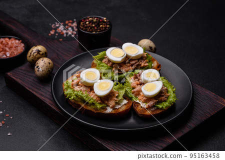 Delicious fresh sandwiches with toast, canned salmon, salad and quail eggs Delicious fresh sandwiches with toast, canned salmon, salad and quail eggs 95163458