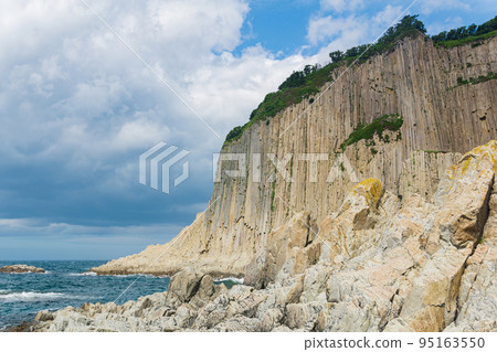 ocean shore with rocks of columnar basalt, Cape Stolbchaty on Kunashir Island 95163550