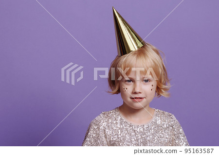 Child in a festive cap on a purple background. Child in a festive cap on a purple background. 95163587