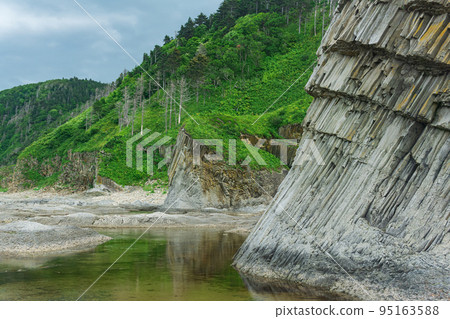 foot of a coastal cliff composed of columnar basalt, on the island of Kunashir 95163588