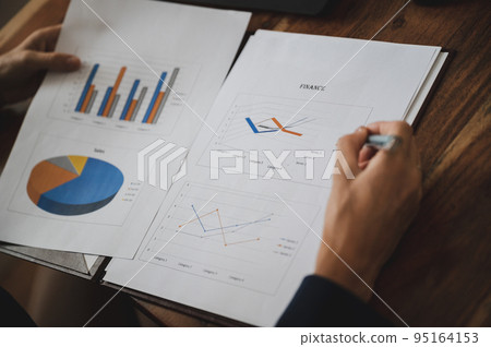 Over the shoulder view of a businesswoman reviewing business and economic report Over the shoulder view of a businesswoman reviewing business and economic report 95164153