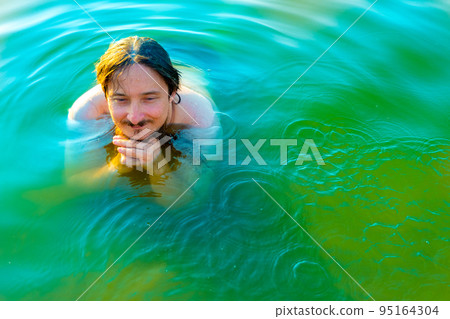 caucasian man floating in a swimming lake with blue water 95164304