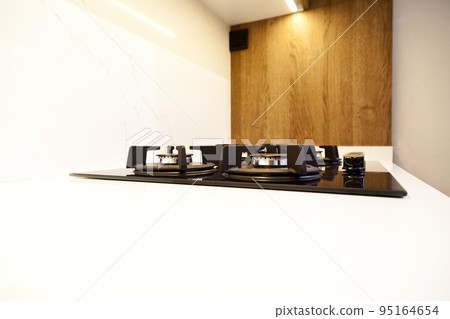 Modern brown wood oak kitchen cabinet equipment, white granite countertops and glass gas stove in a home Modern brown wood oak kitchen cabinet equipment, white granite countertops and glass gas stove in a home 95164654